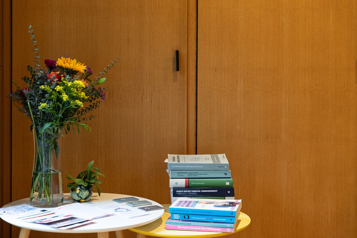 Twee tafeltjes met daarop allerlei boeken over Bemiddeling en een boekt in een glazen vaas